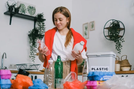 Woman sorting plastic bottles in kitchen - nine ways to reduce waste in your home