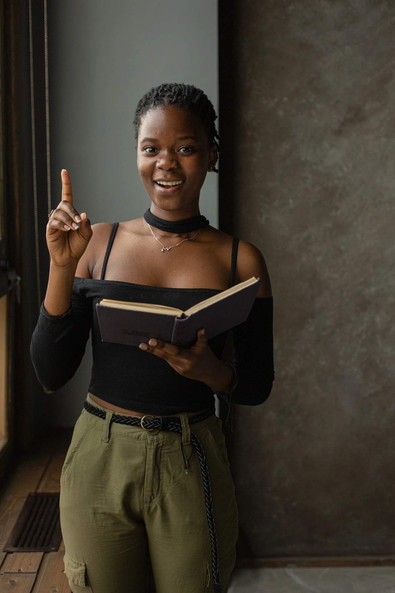 dark skinned woman holding a book, looking excited