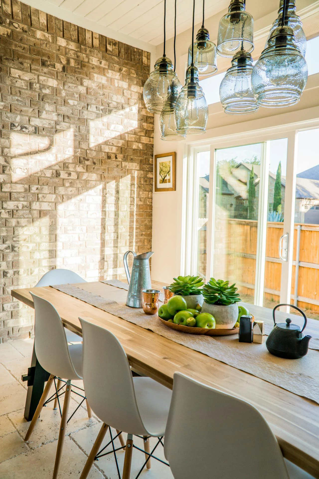 bright kitchen with wooden table, patio doors, and exposed brickwork wall