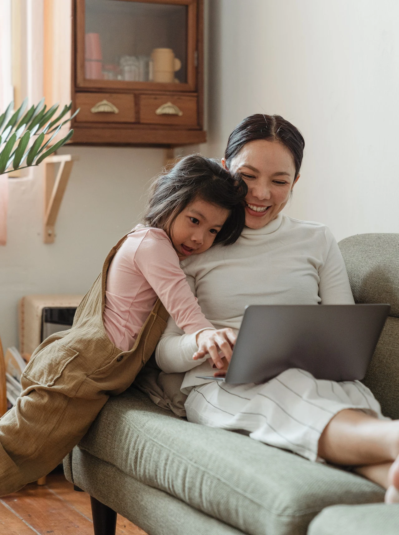 Happy mother using laptop with daughter