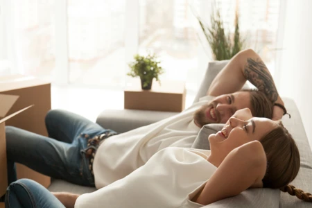 Relieved looking couple leaning back on a sofa