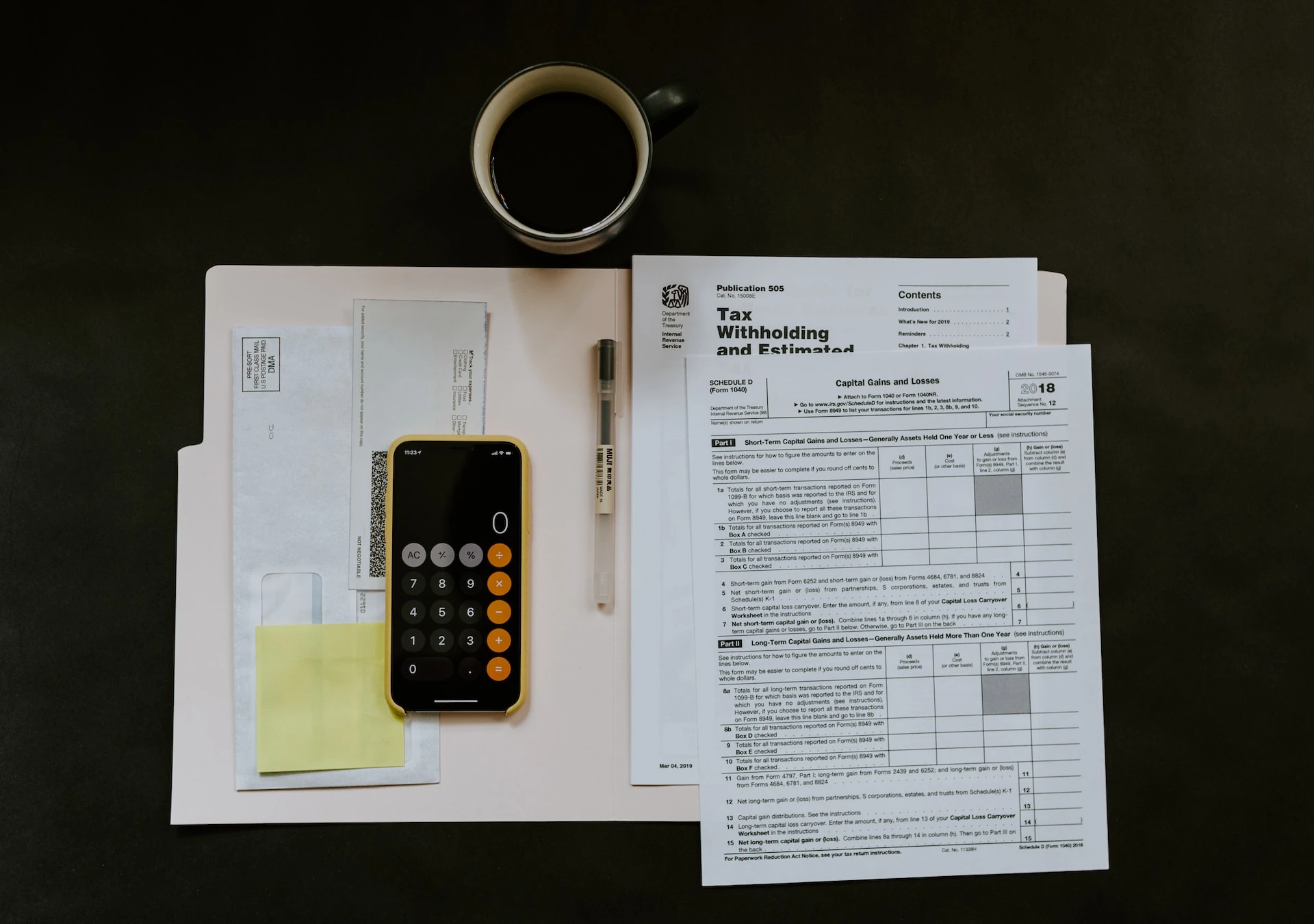 Paperwork in open binder on black table with phone and coffee cup nearby