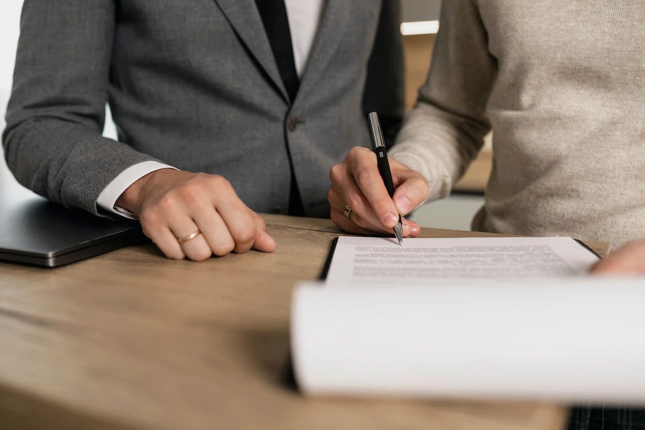 Man signing a contract next to a man in a suit