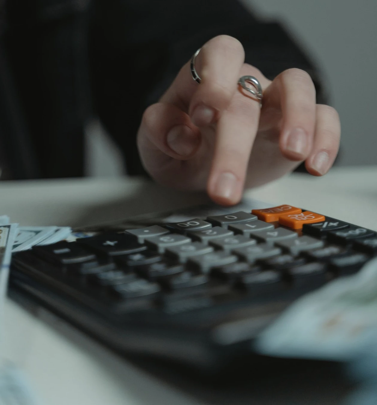 Persons hand using a calculator on a tabletop