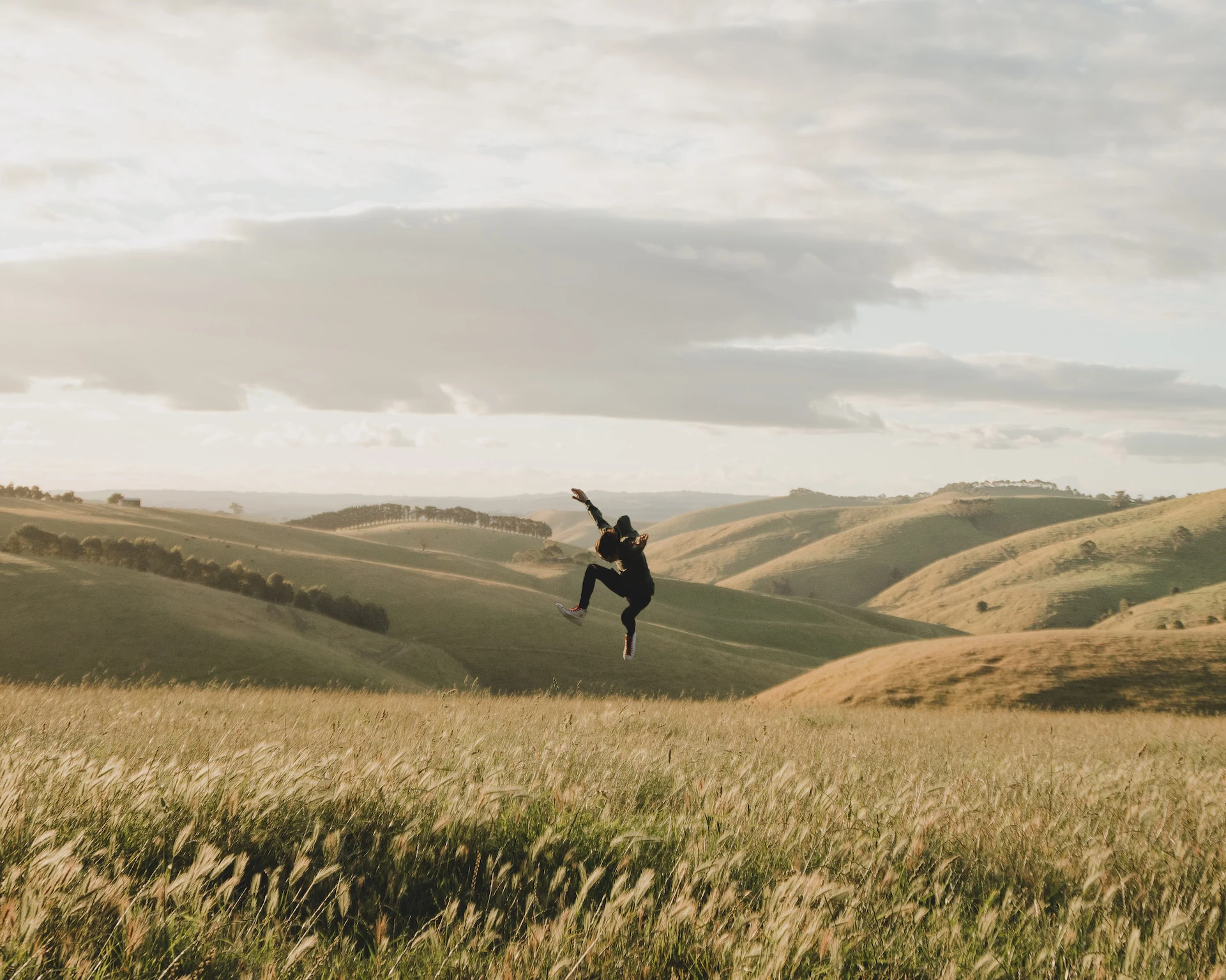 person jumping over long grass field