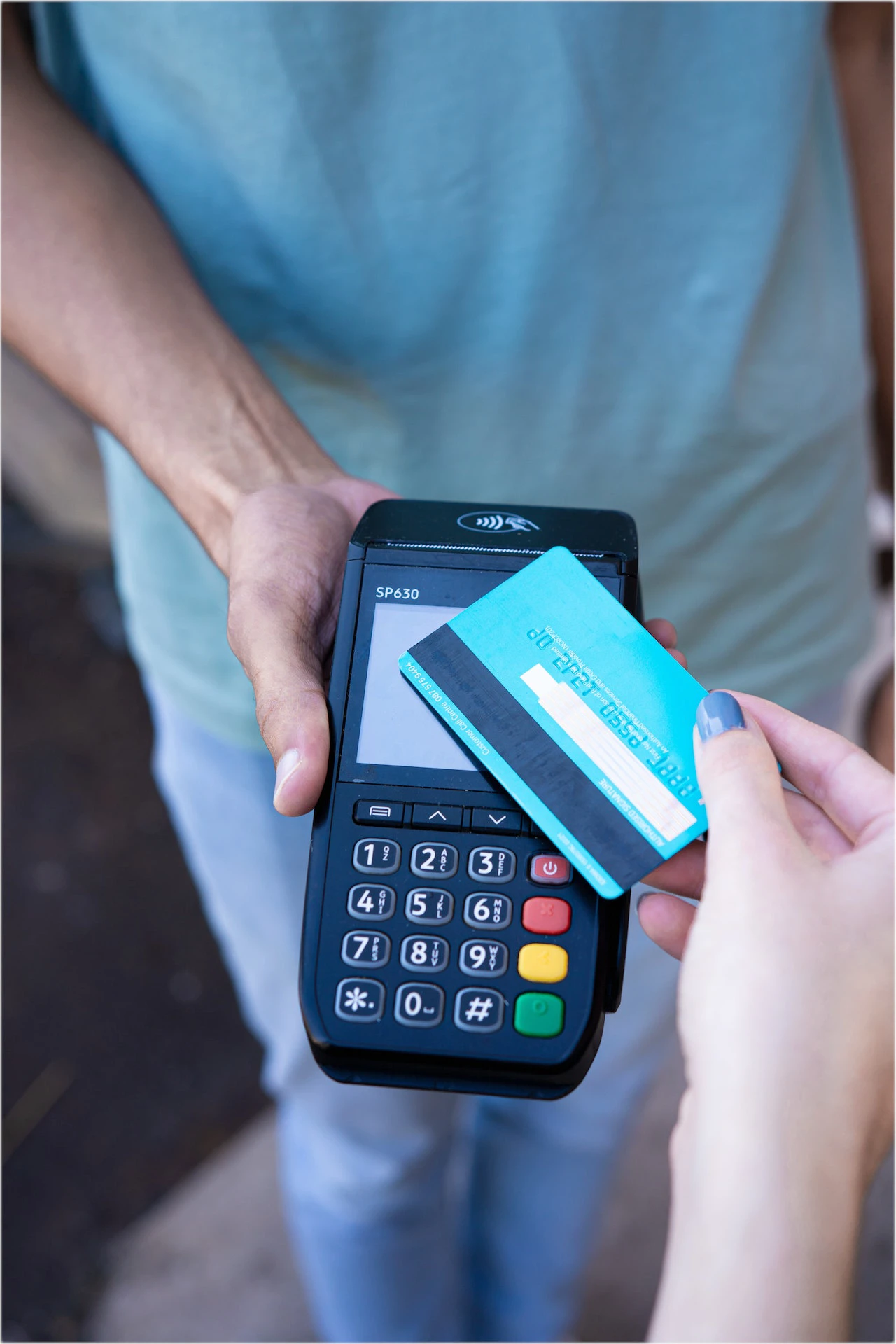 contactless payment device with someone holding a debit card over it - how to remortgage if you're self eemployed