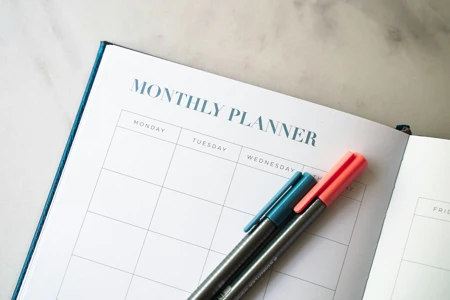 open calendar monthly planner with two pens laying on top