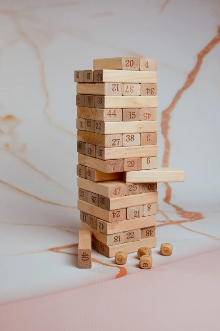 Numbered stack of jenga pieces in a tower, dice in front
