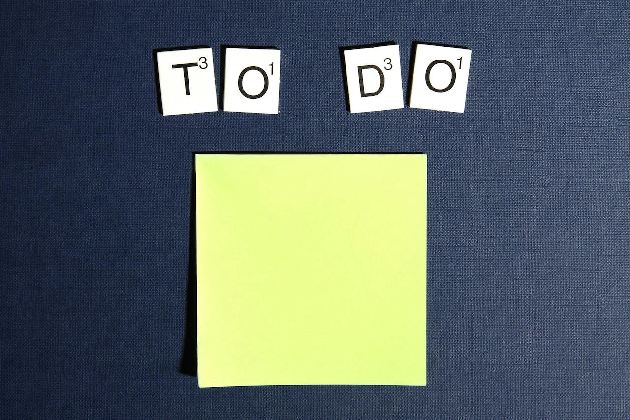 bright yellow sticky note on dark background with scrabble to do letters at the top
