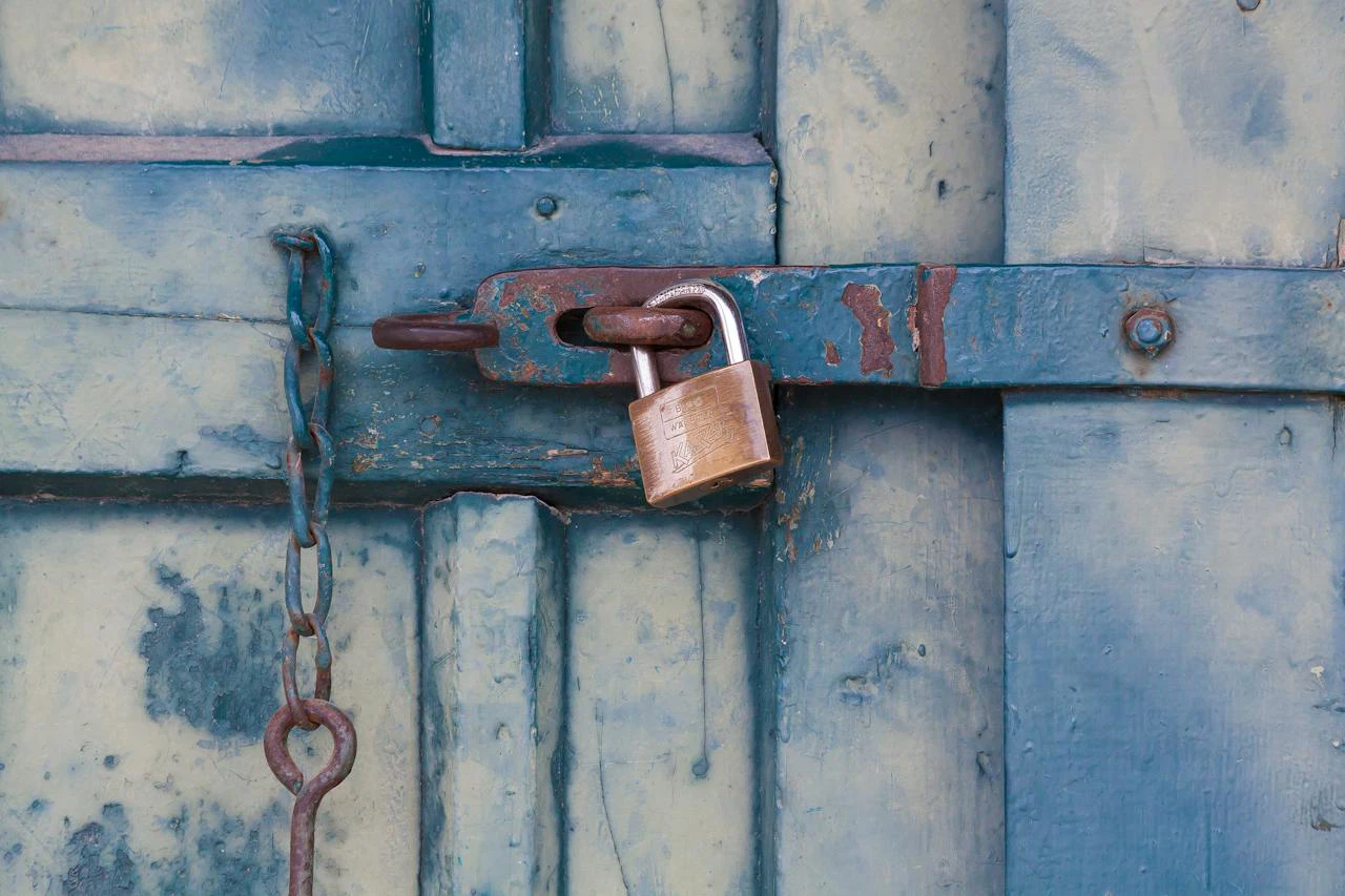 brass lock holding a blue bolted outdoor door closed