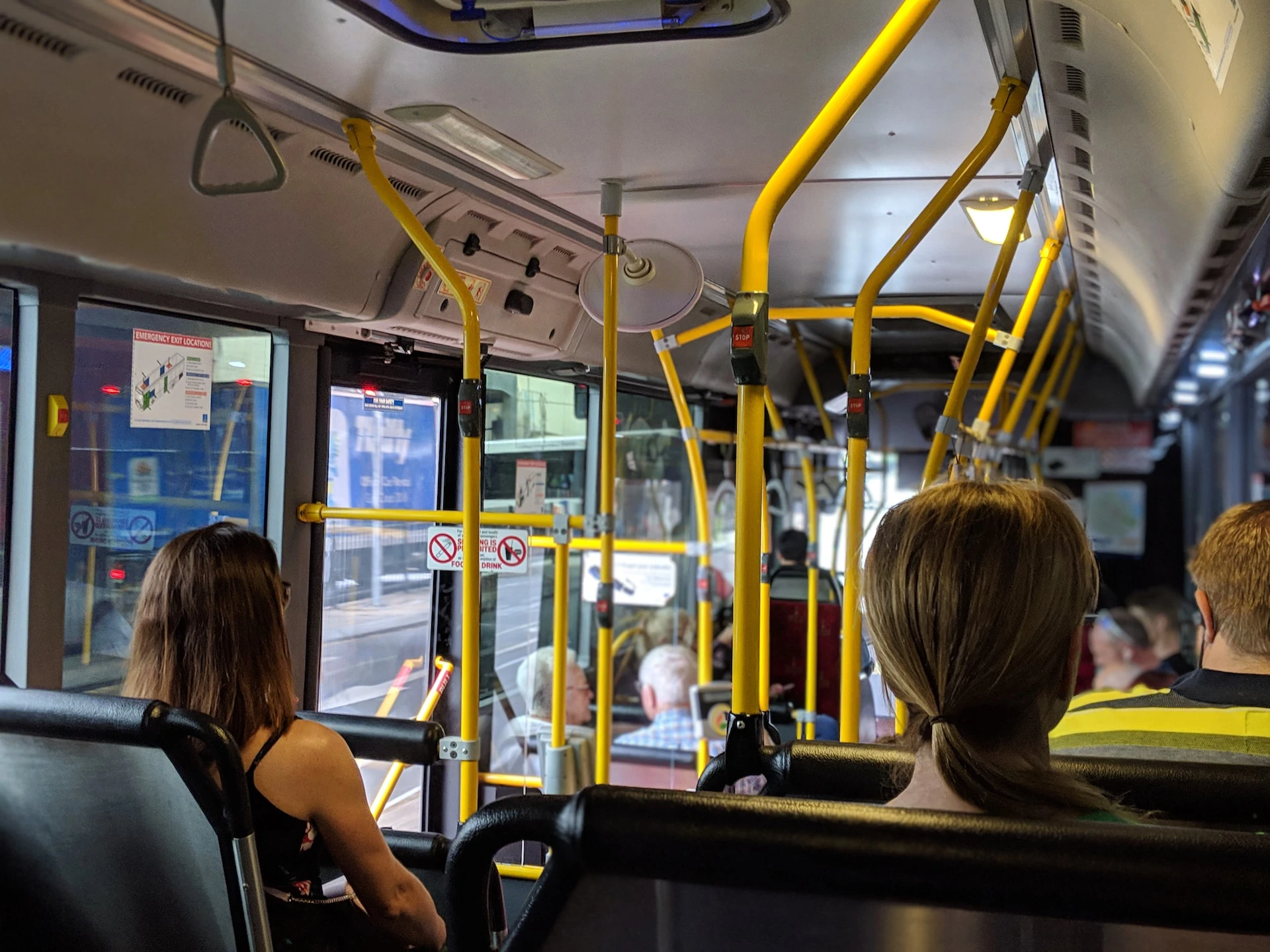 inside view of a bus with two people sitting down and yellow bars across the top