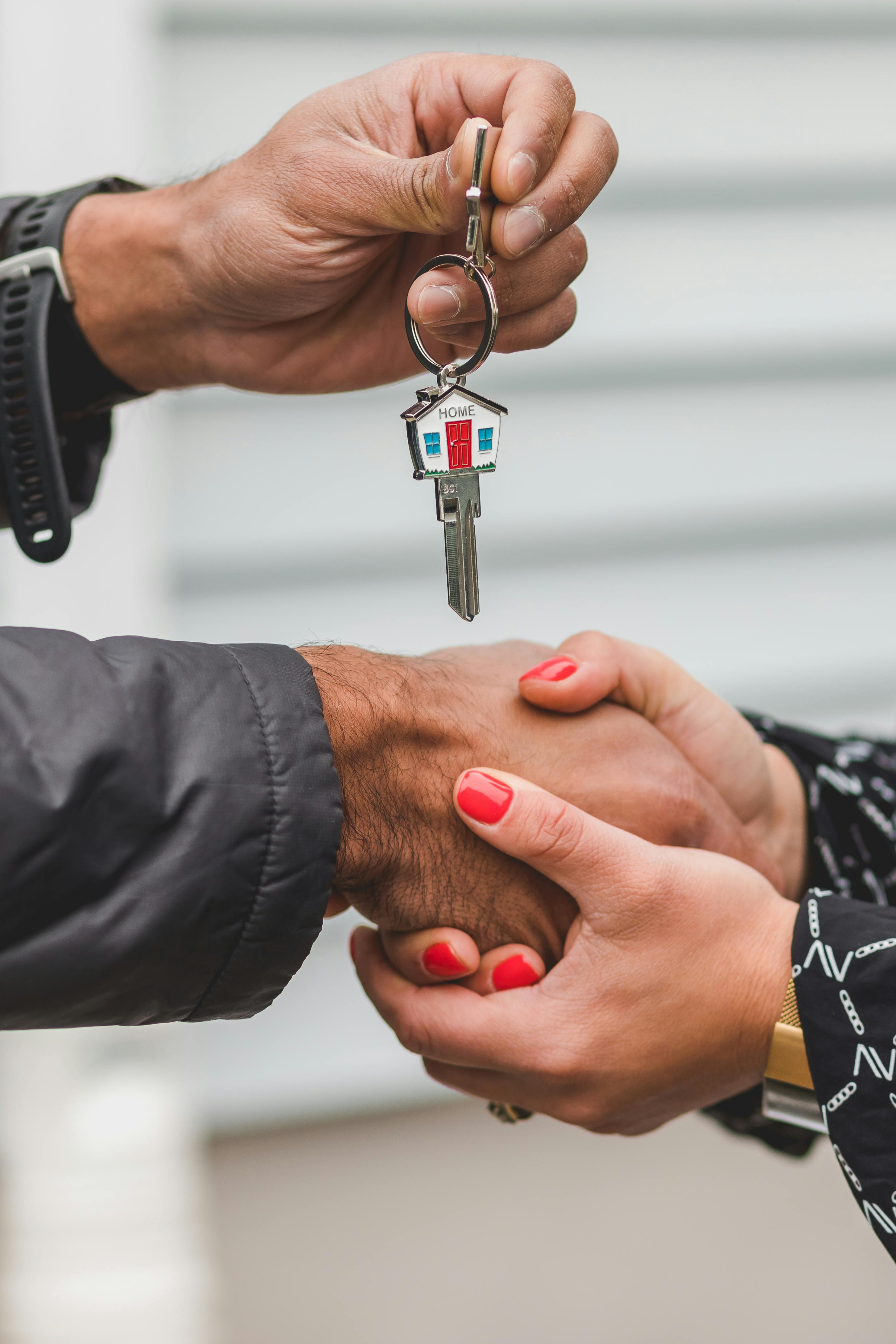 person holding a house key shaking hands