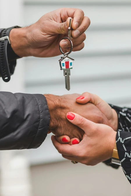person holding a house key shaking hands