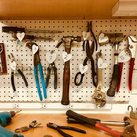 set of tools labelled with numbers against white pegboard