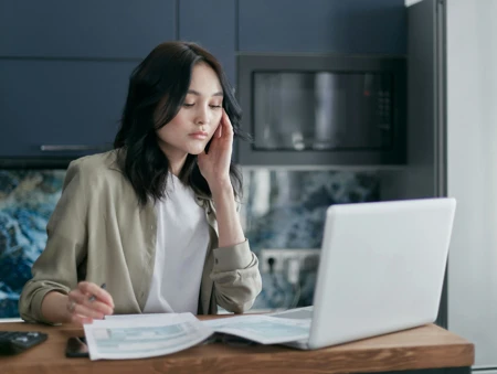 woman on computer sat at desk looking at documents