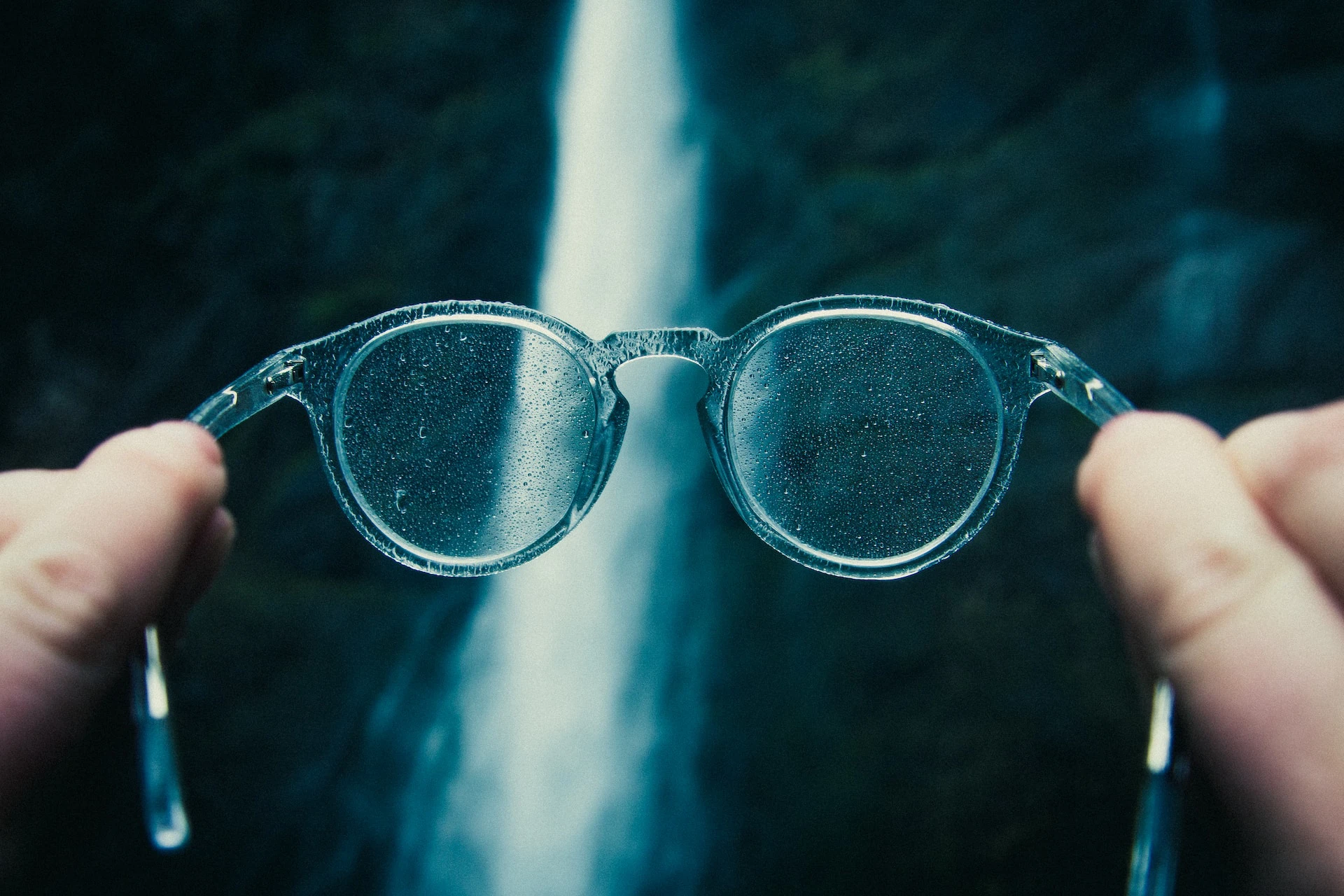 hands holding up glasses with waterdrops on them