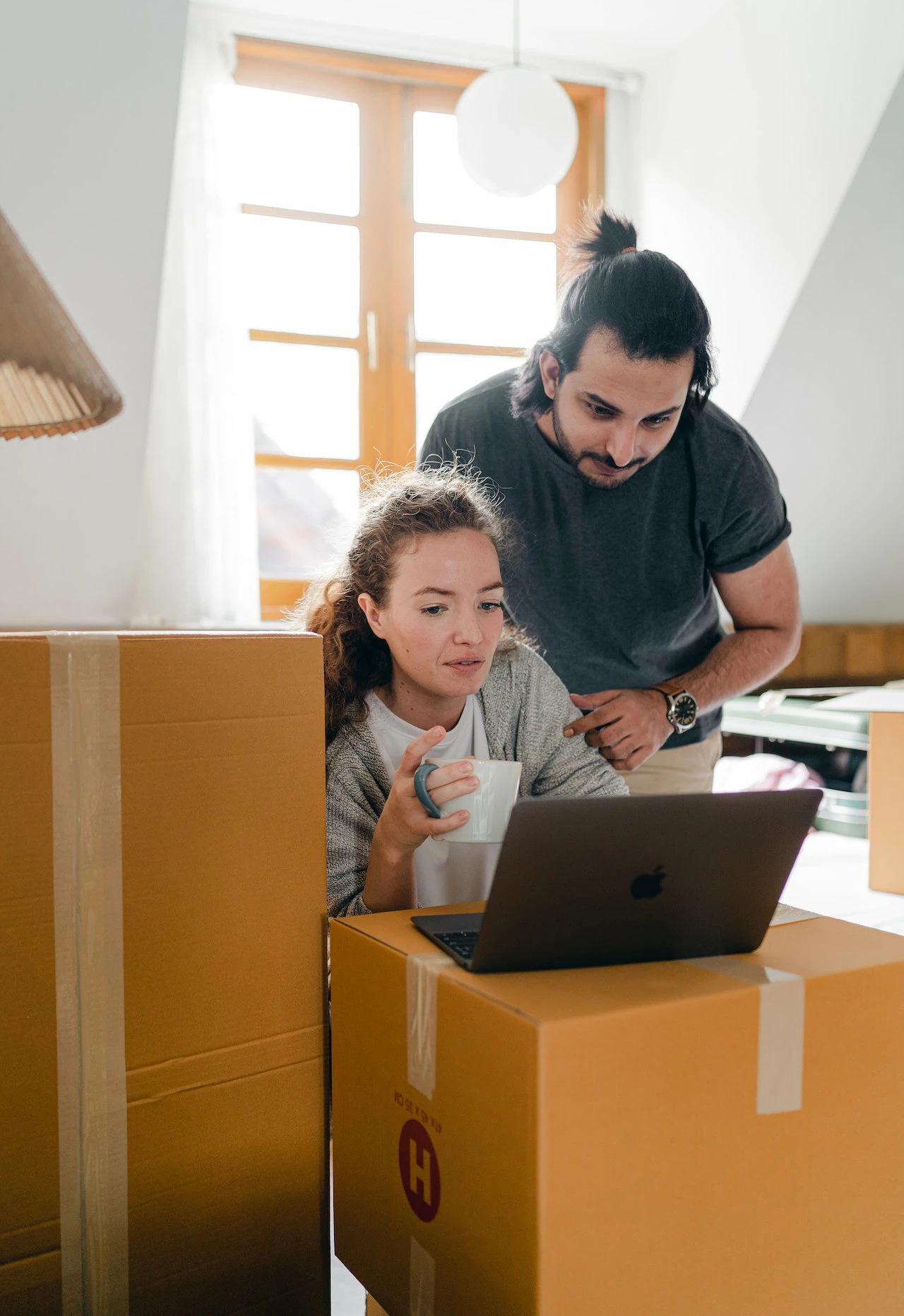 Couple looking at laptop amongst cardboard boxes