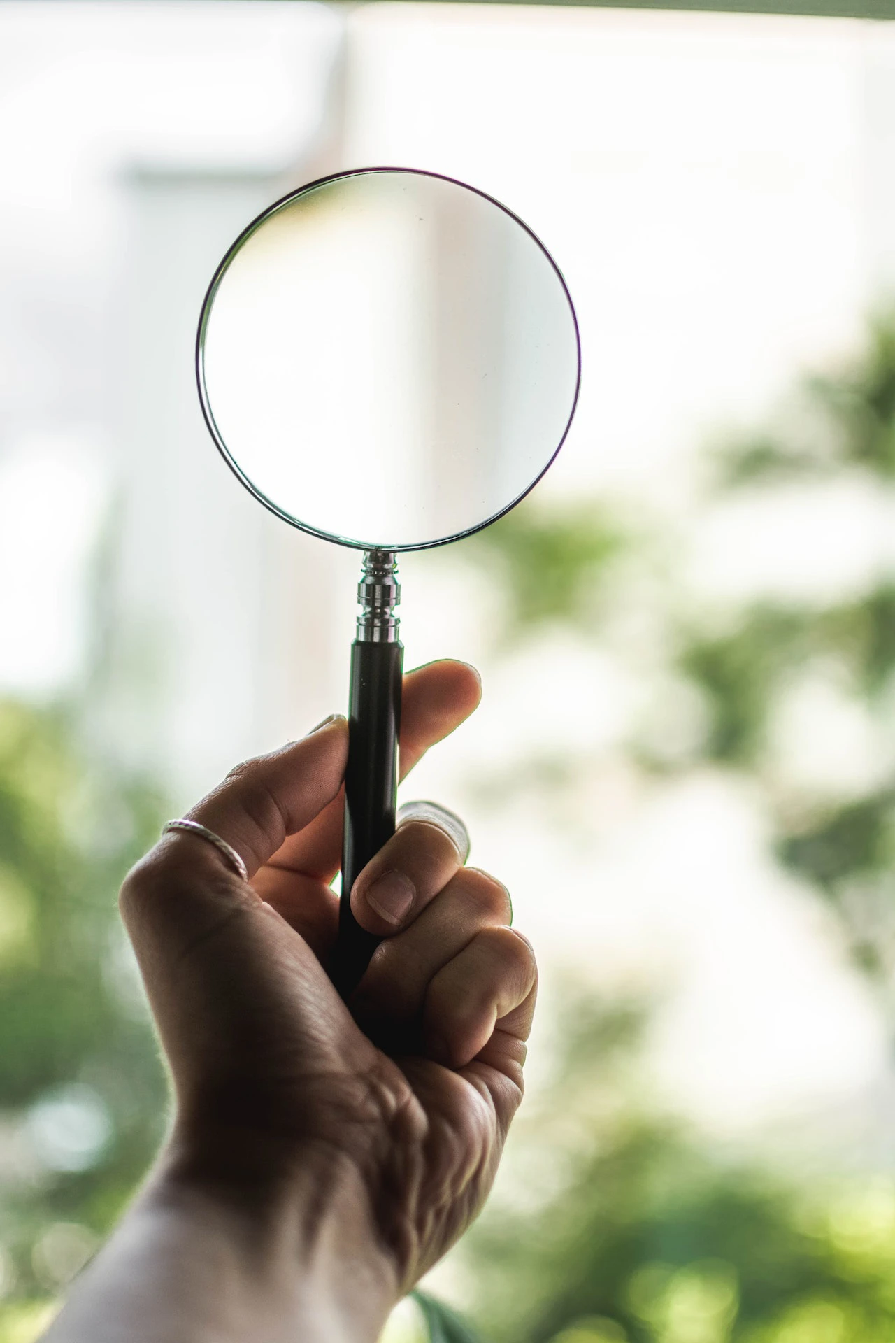 Hand holding up a magnifying glass