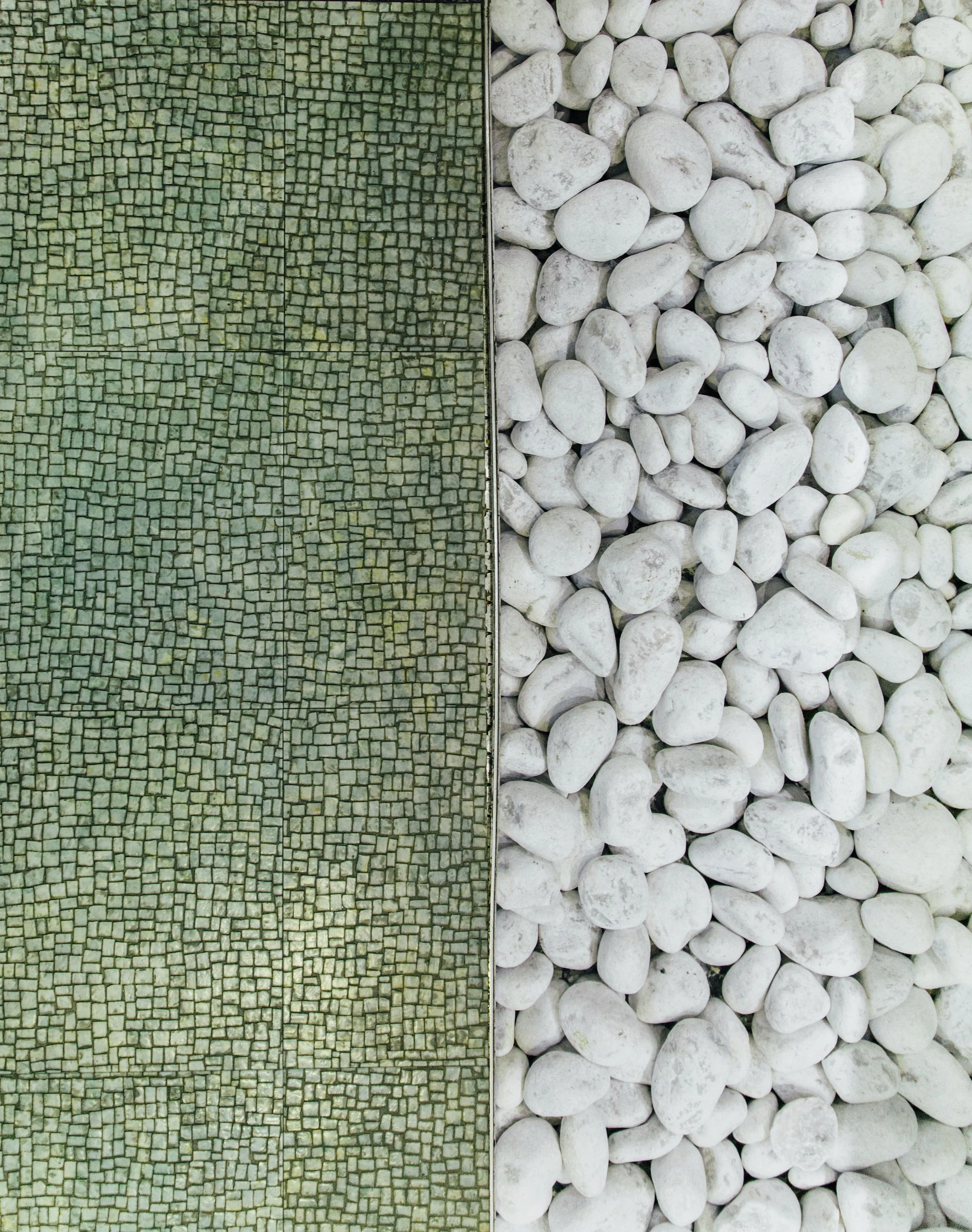 two contrasting materials in a straight vertical line - green stone on the left and white pebbles on the right