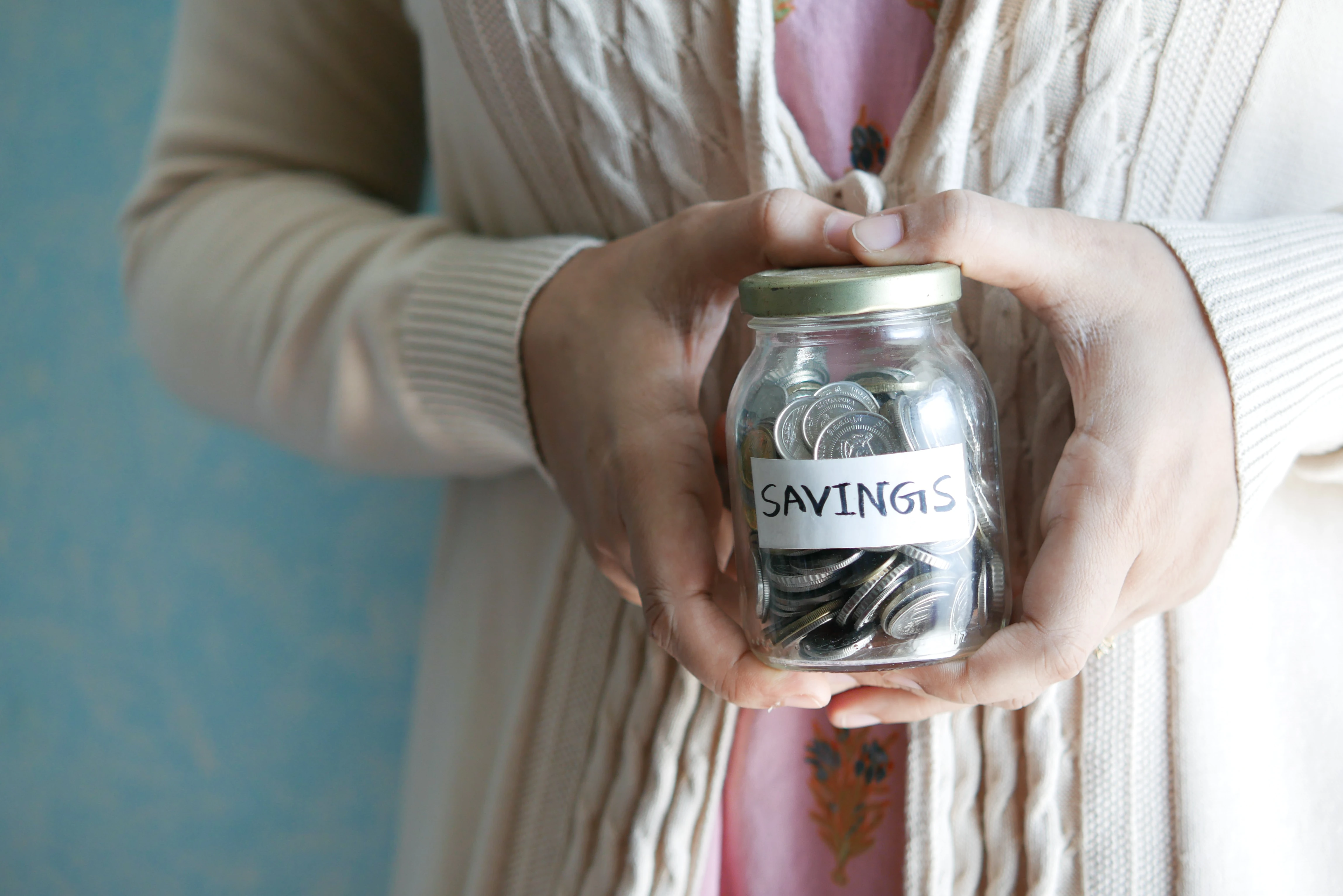 woman holding a jar of coins that says savings on it