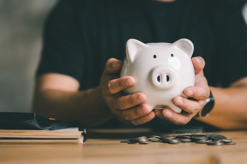 Man hand holding piggy bank on wood table