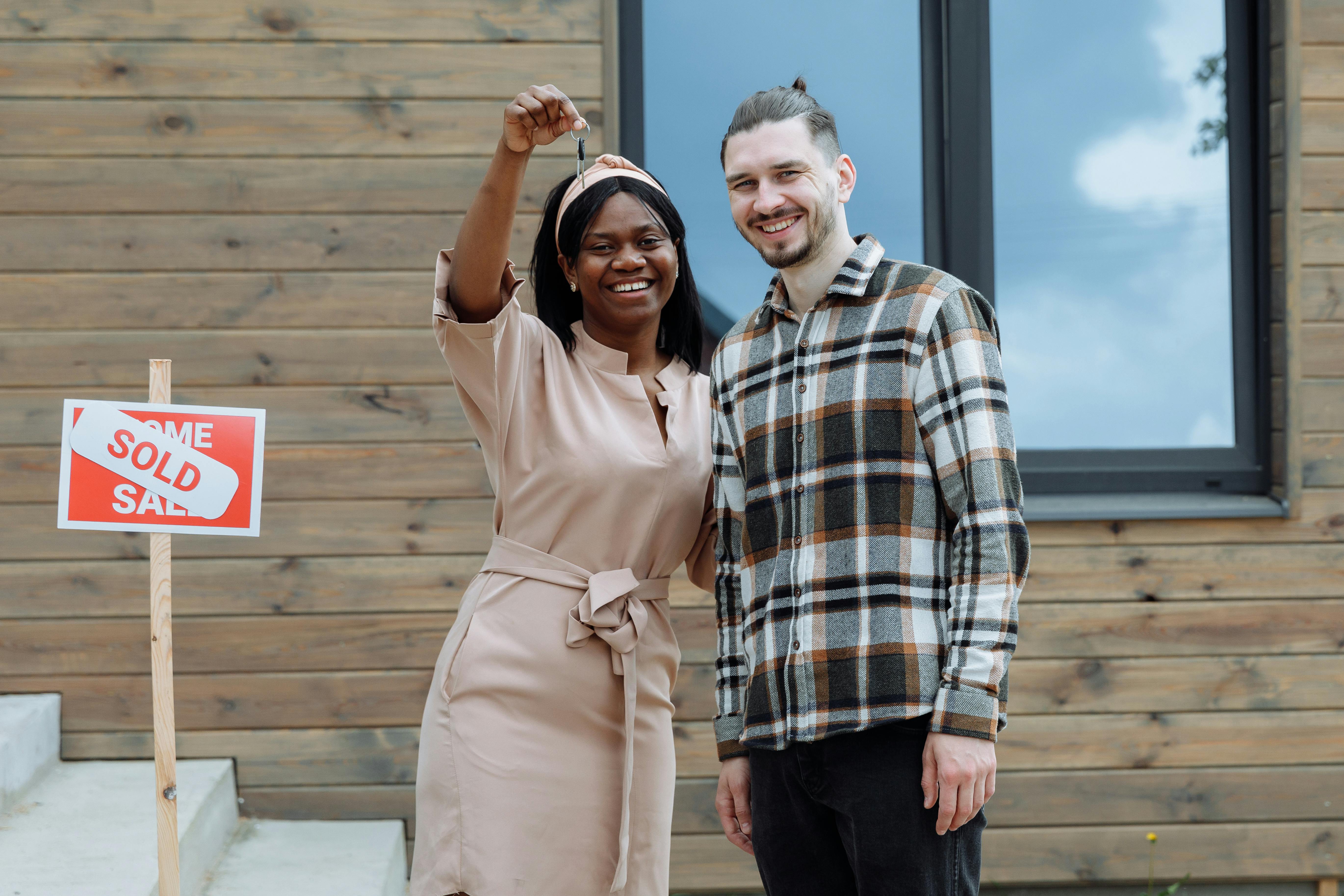 smiling couple holding keys to sold house