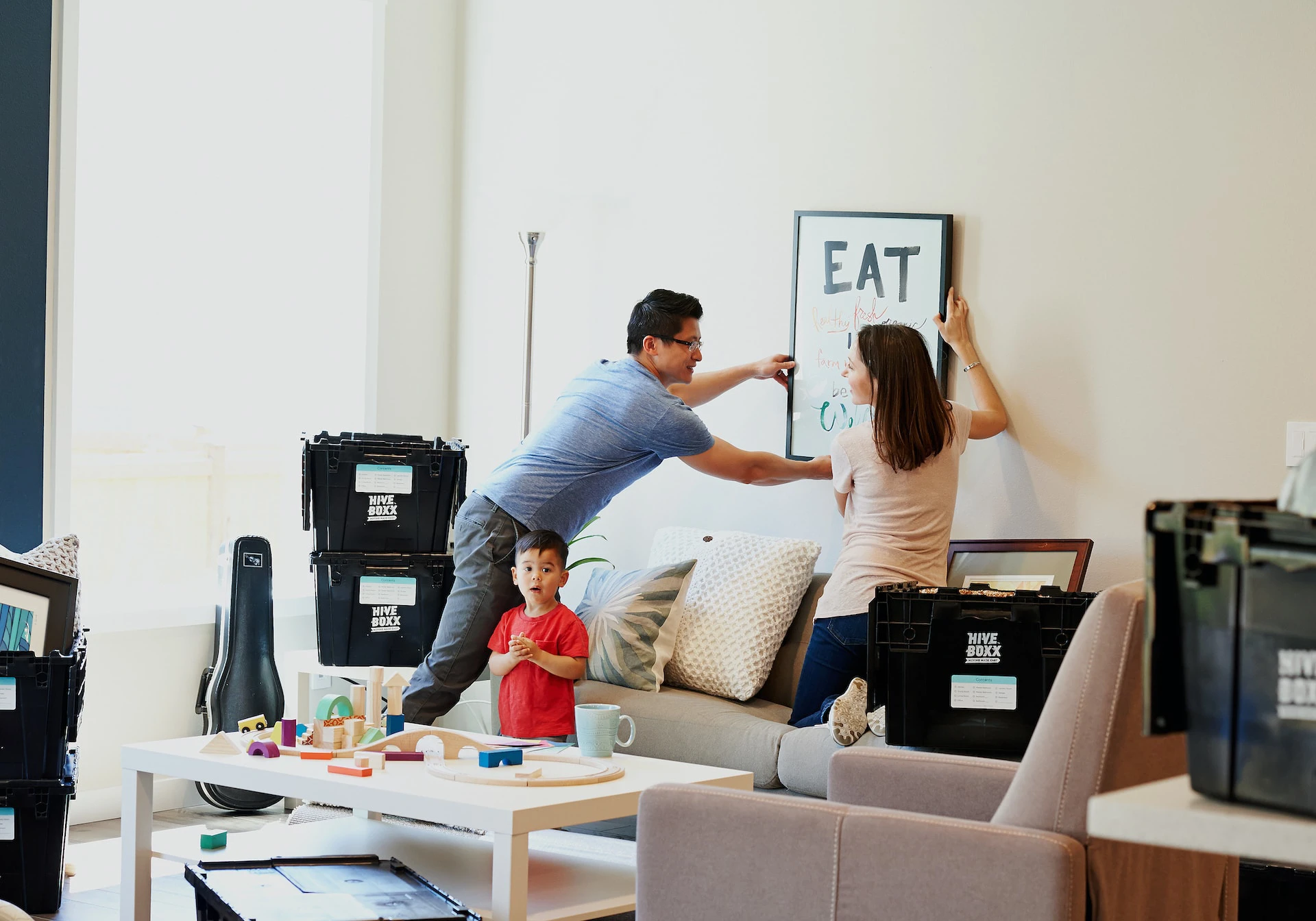 Couple and child putting up picture frame in living room 