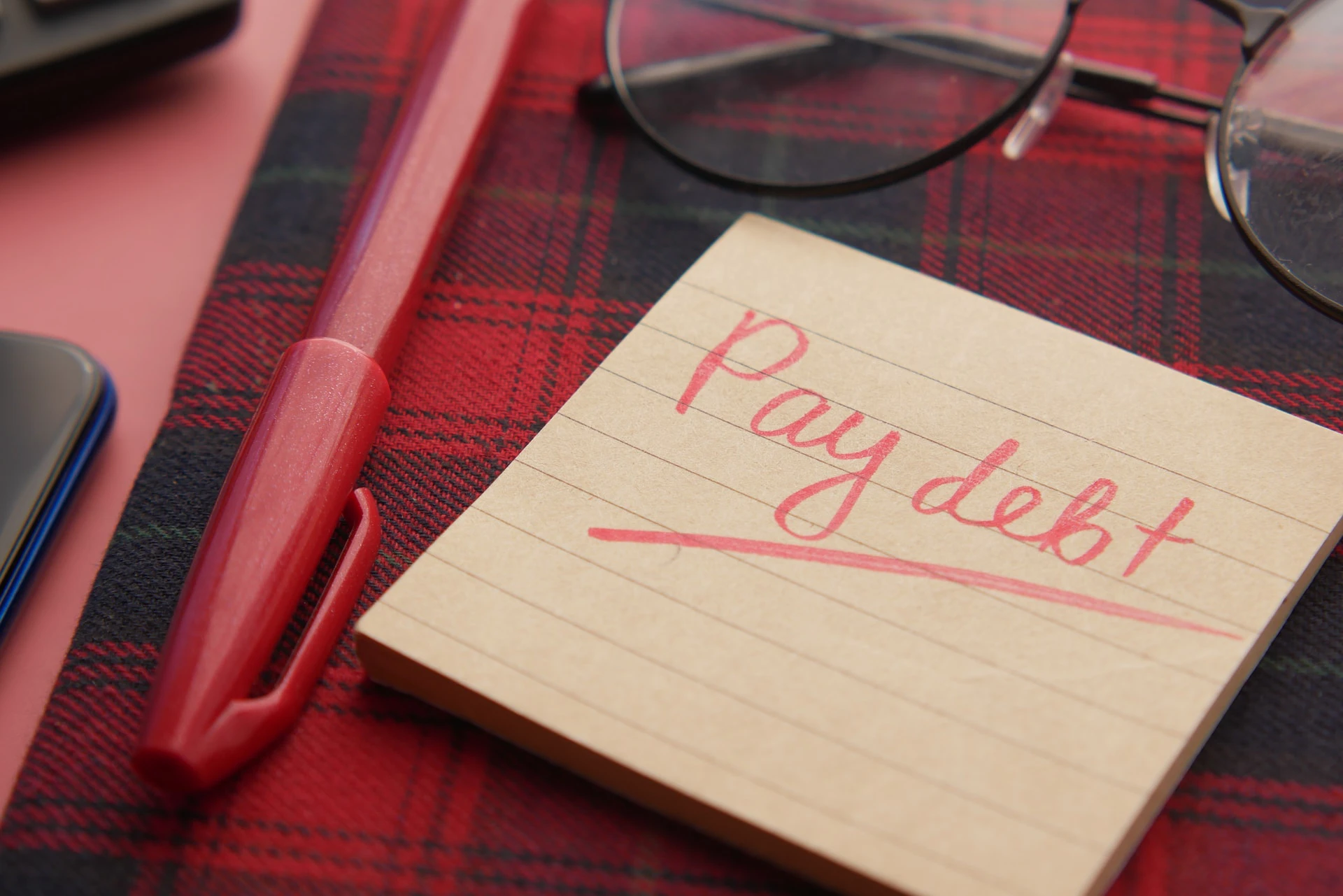 sticky note with the words "pay debt" written in pink