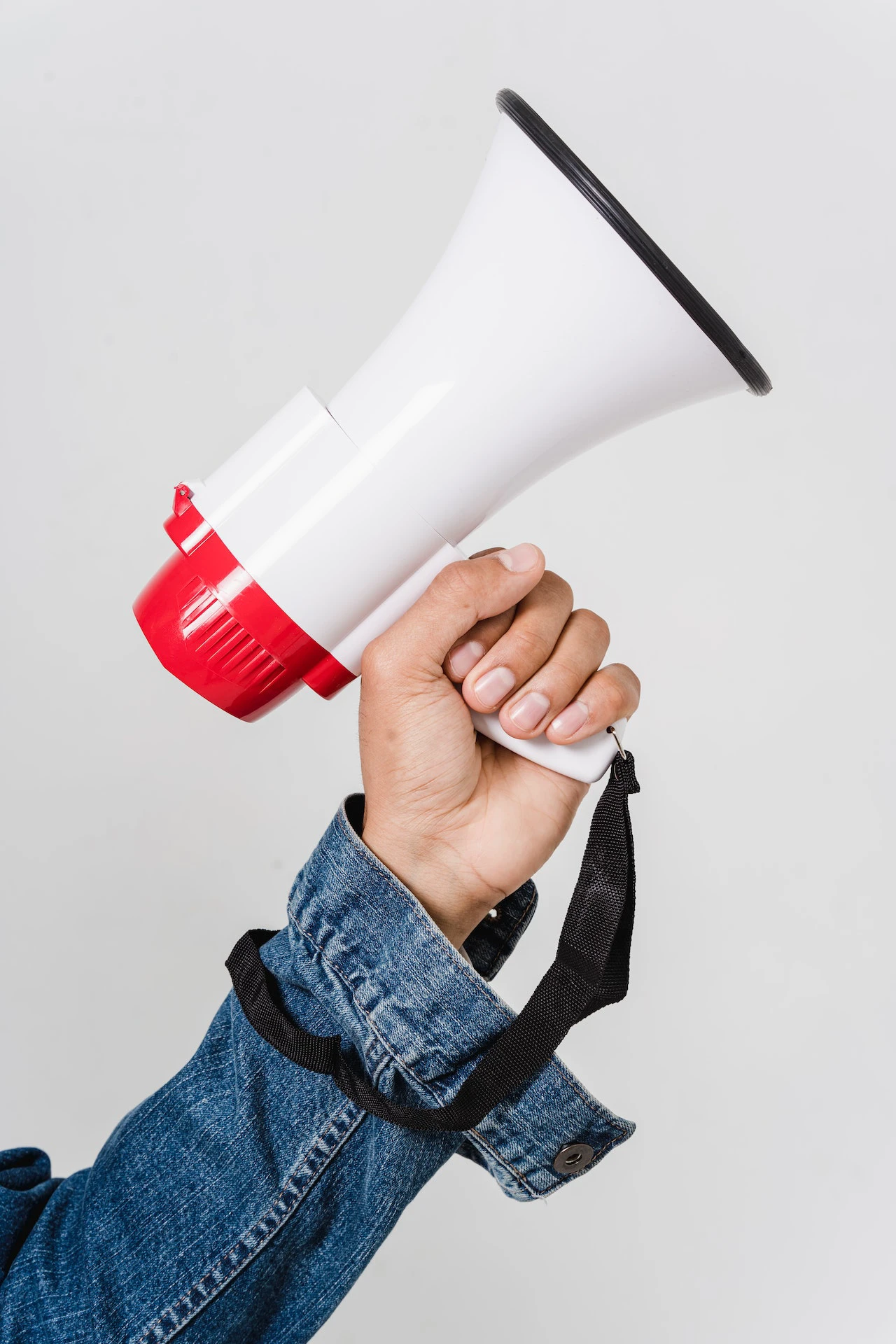 arm in a denim jacket holding a white and red megaphone