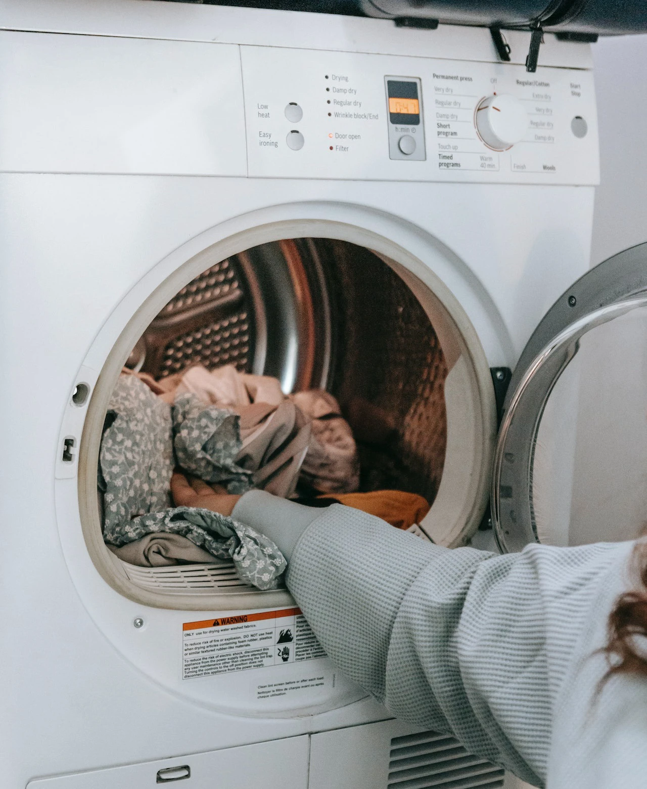 Person taking clothes out of washing machine with one hand