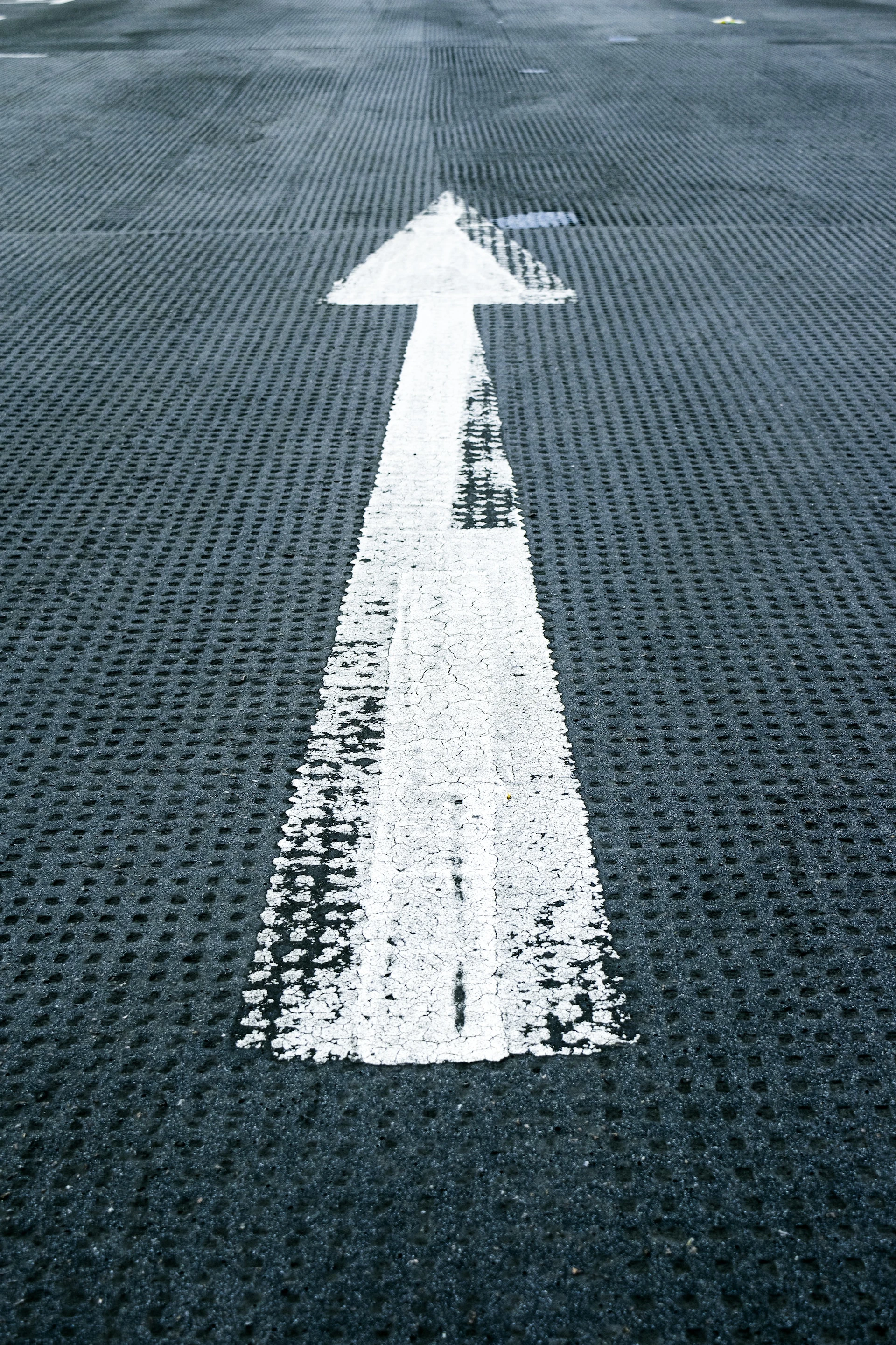 white painted arrow on mesh black plastic floor