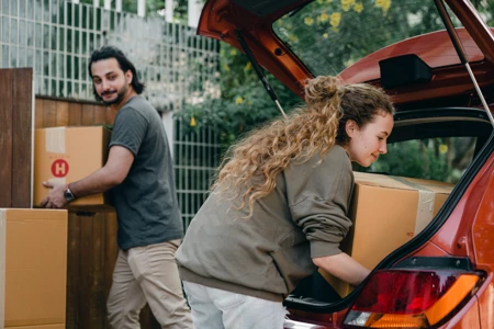 couple unloading boxes from car into new home