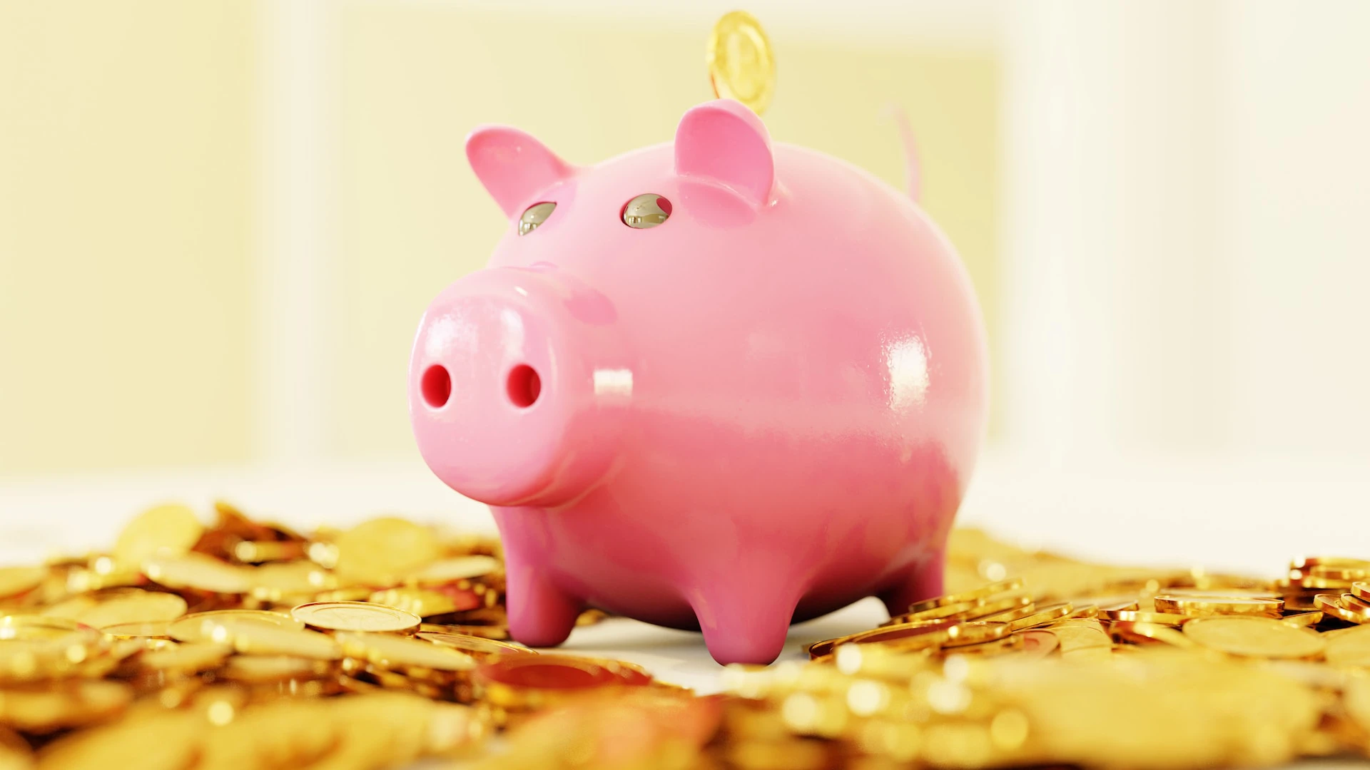 pink piggy bank sitting amongst gold coins
