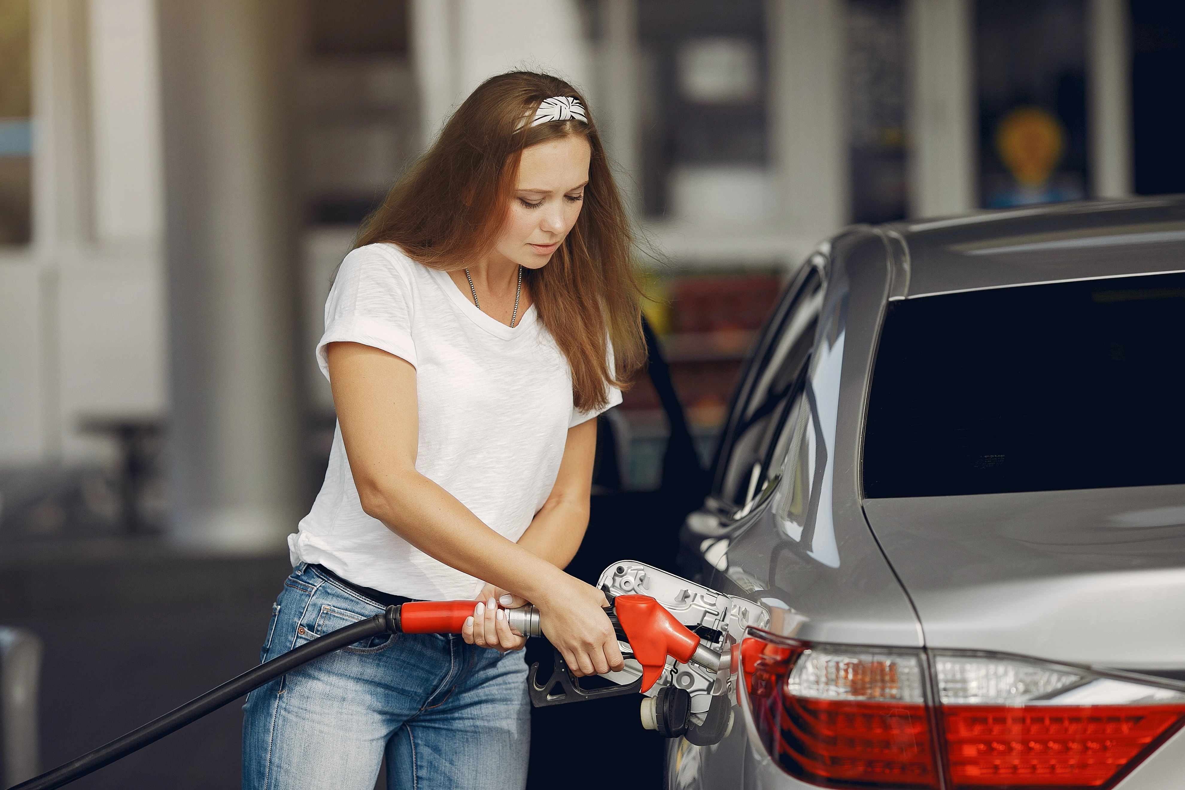 woman refuelling car - Rate of inflation drops; major lenders lower fixed rates