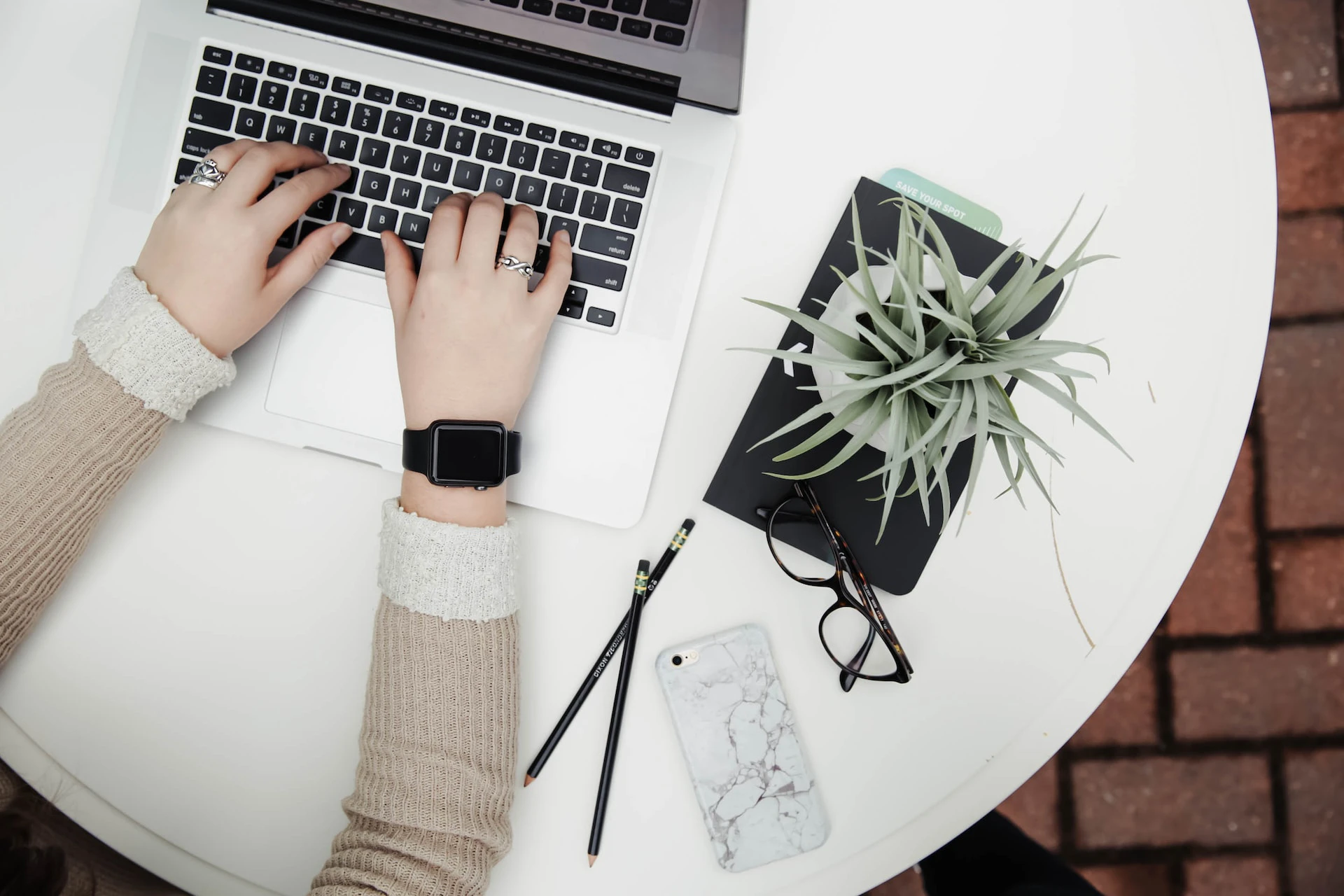 woman in grey jumper typing on laptop birds eye view