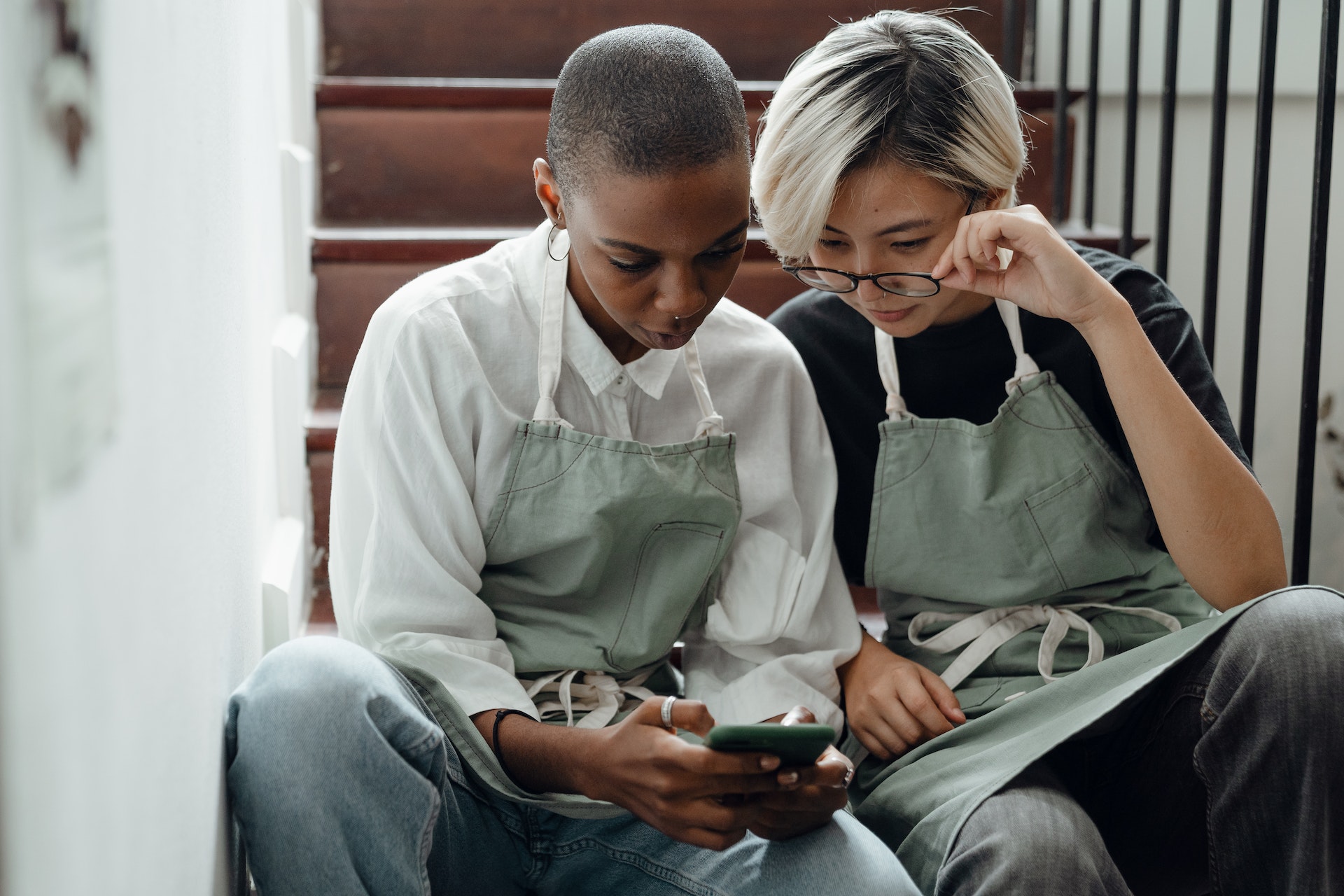 Two women looking at a smart phone while sitting on stairs