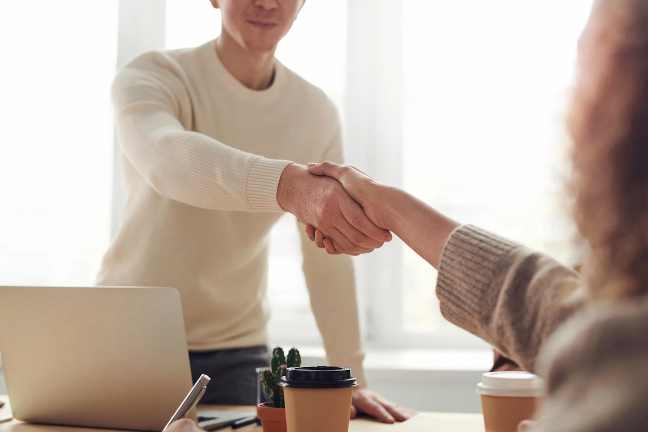 man and woman shaking hands over desk