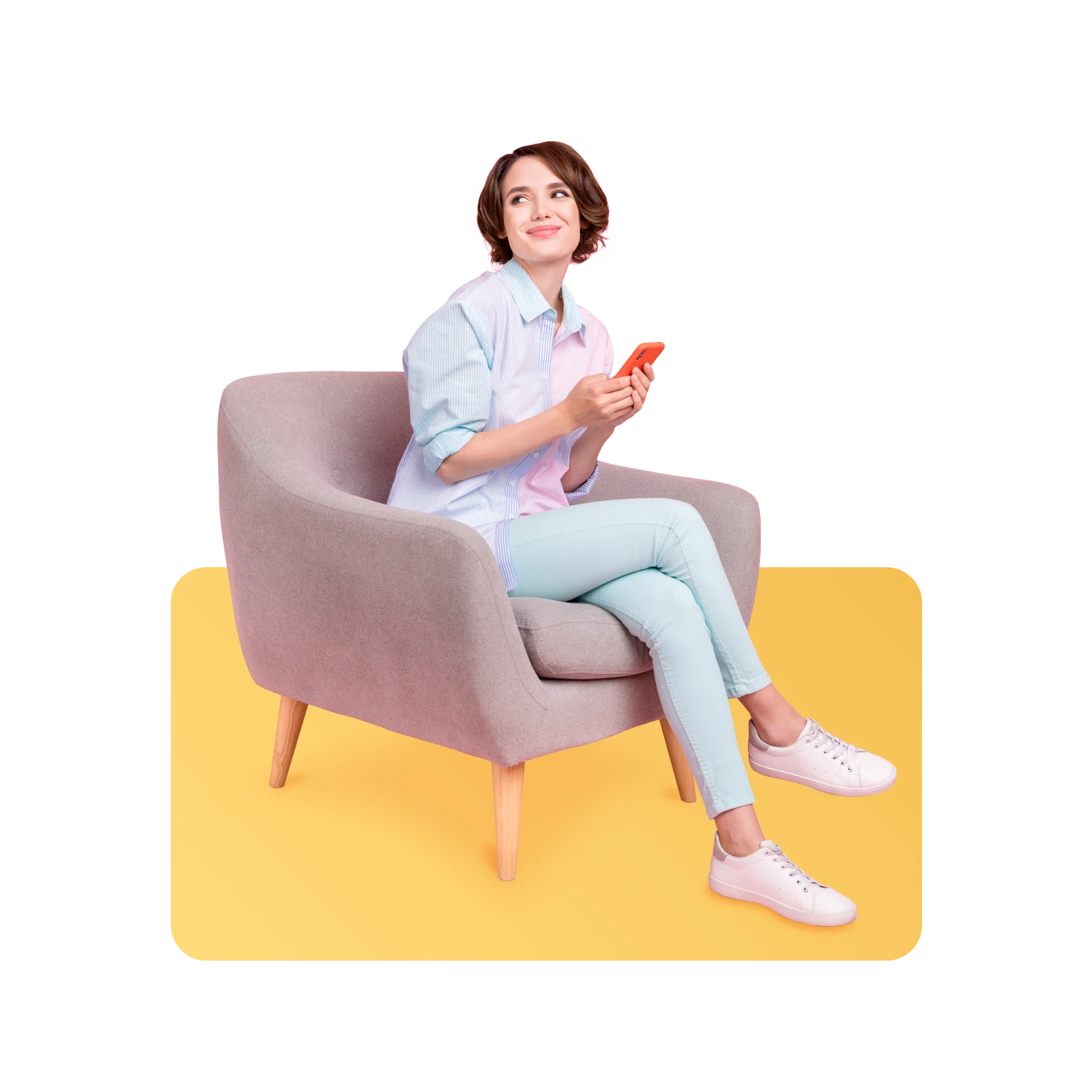 woman sitting in soft grey chair on yellow background, looking at her phone