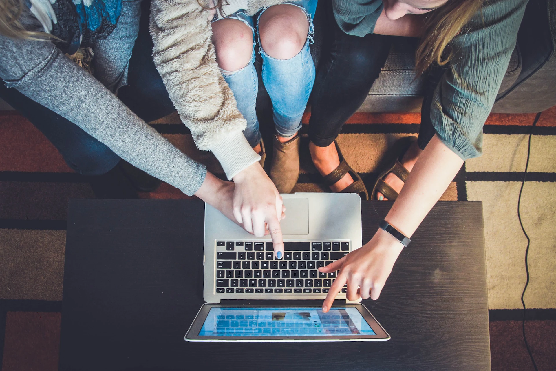 three people looking at laptop screen and pointing