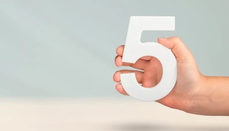 A hand holding the number 5