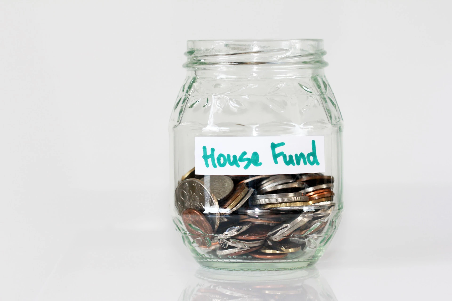 clear jar filled with coins and a label that says "house fund"