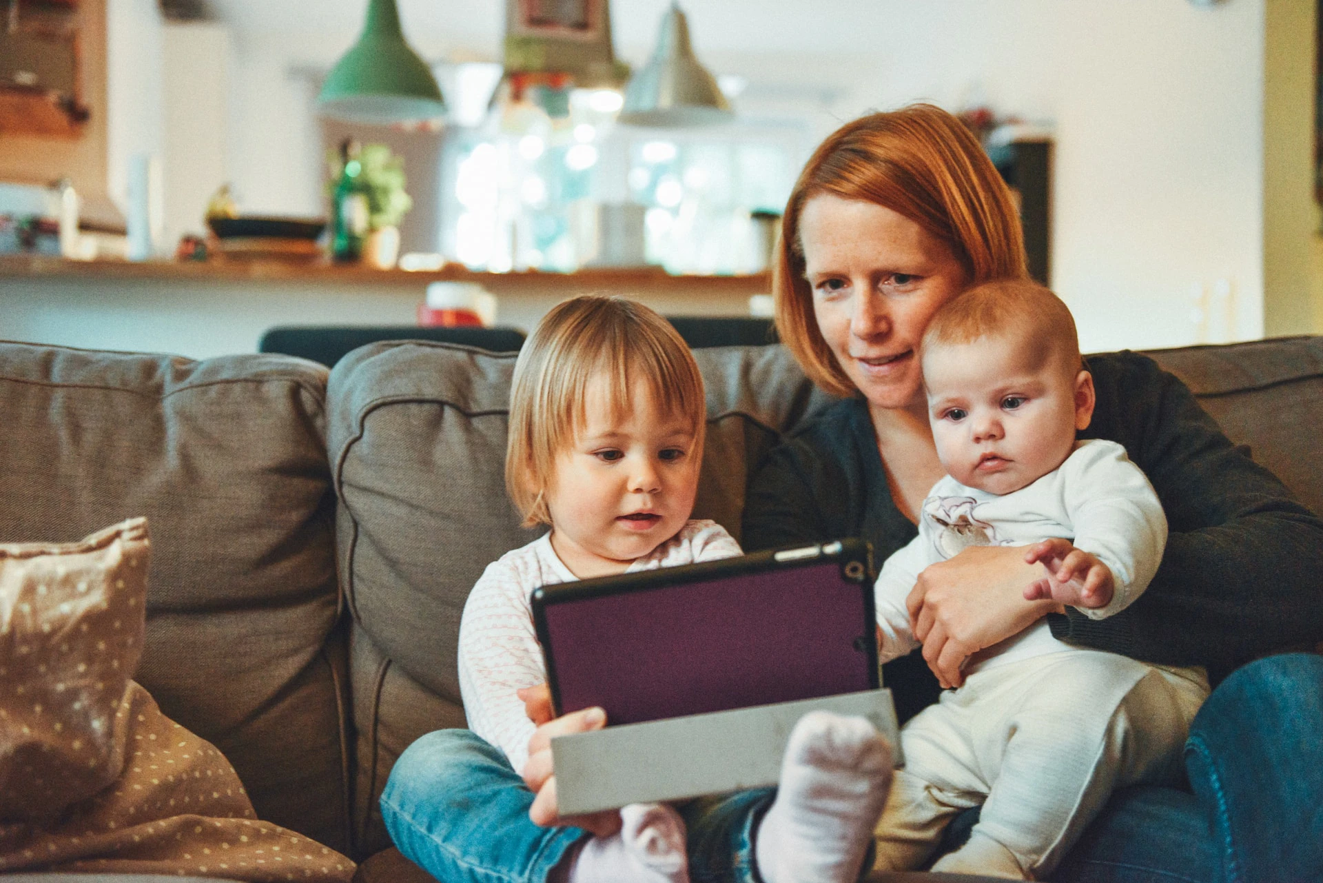 mother showing something to toddler and baby on tablet