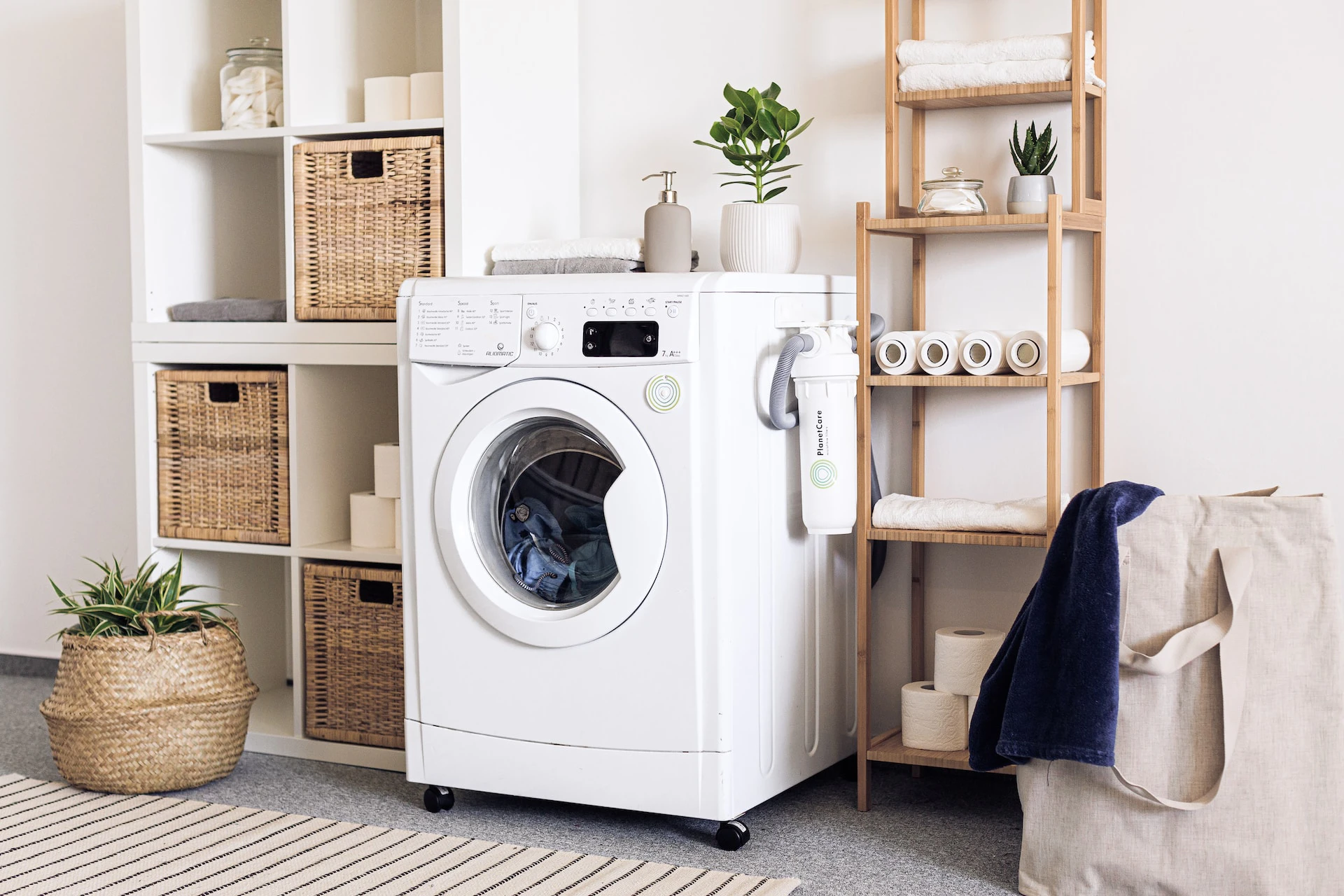 A white washing machine in a utility room surrounded by shelves and a laundry bag