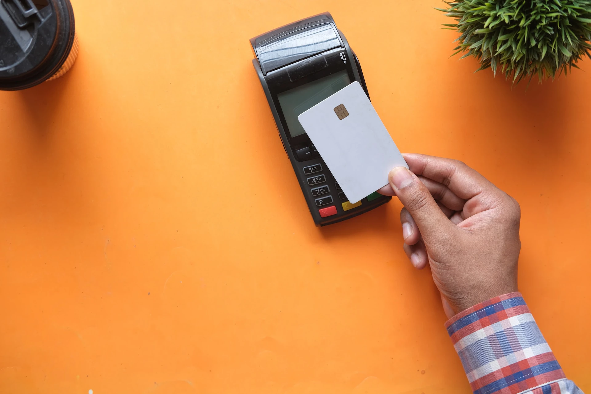 blank card with microchip tapping a card machine against an orange background