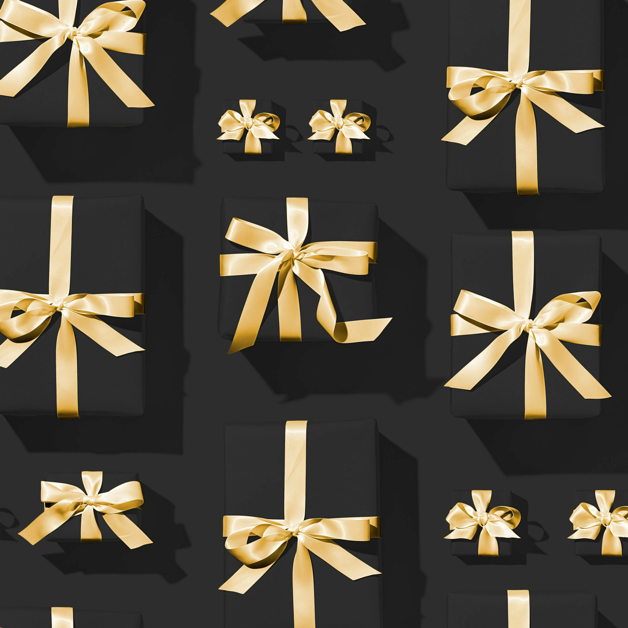 Gifts on black background wrapped in black paper and gold ribbons