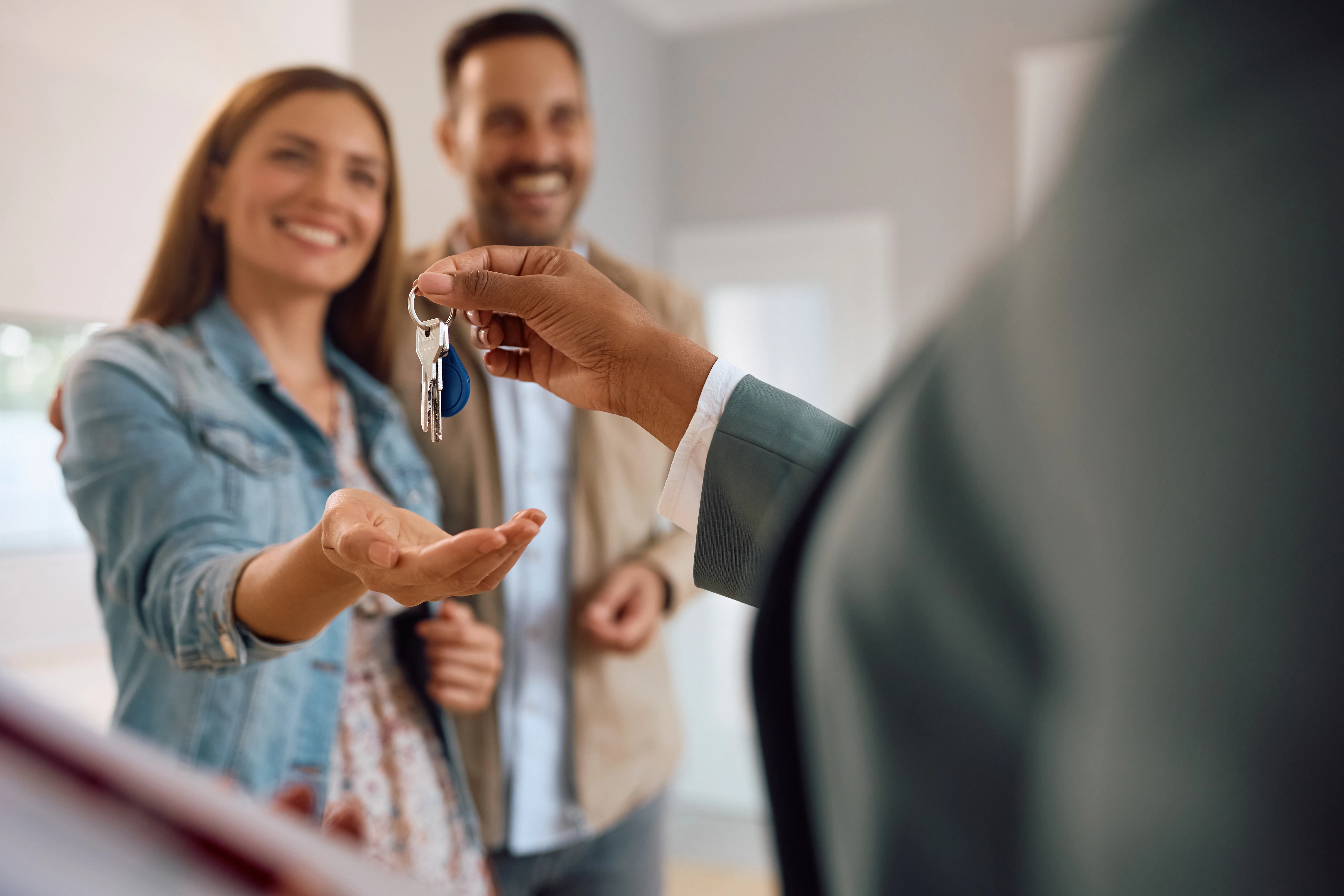 Couple holding out hand for adviser to hand over keys