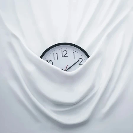 Clock half hidden by white fabric hanging down