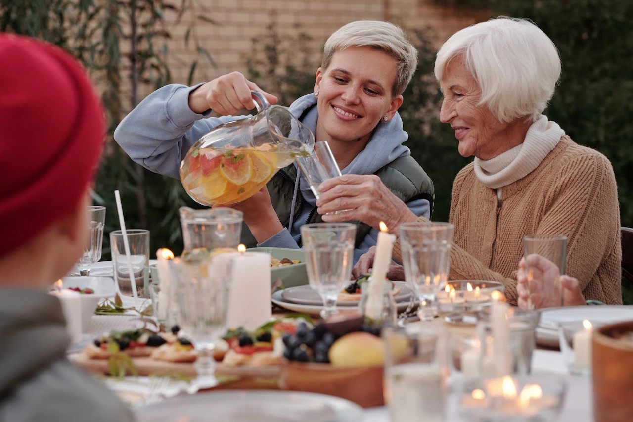 Younger woman pouring drink into older woman's glass at dinner table