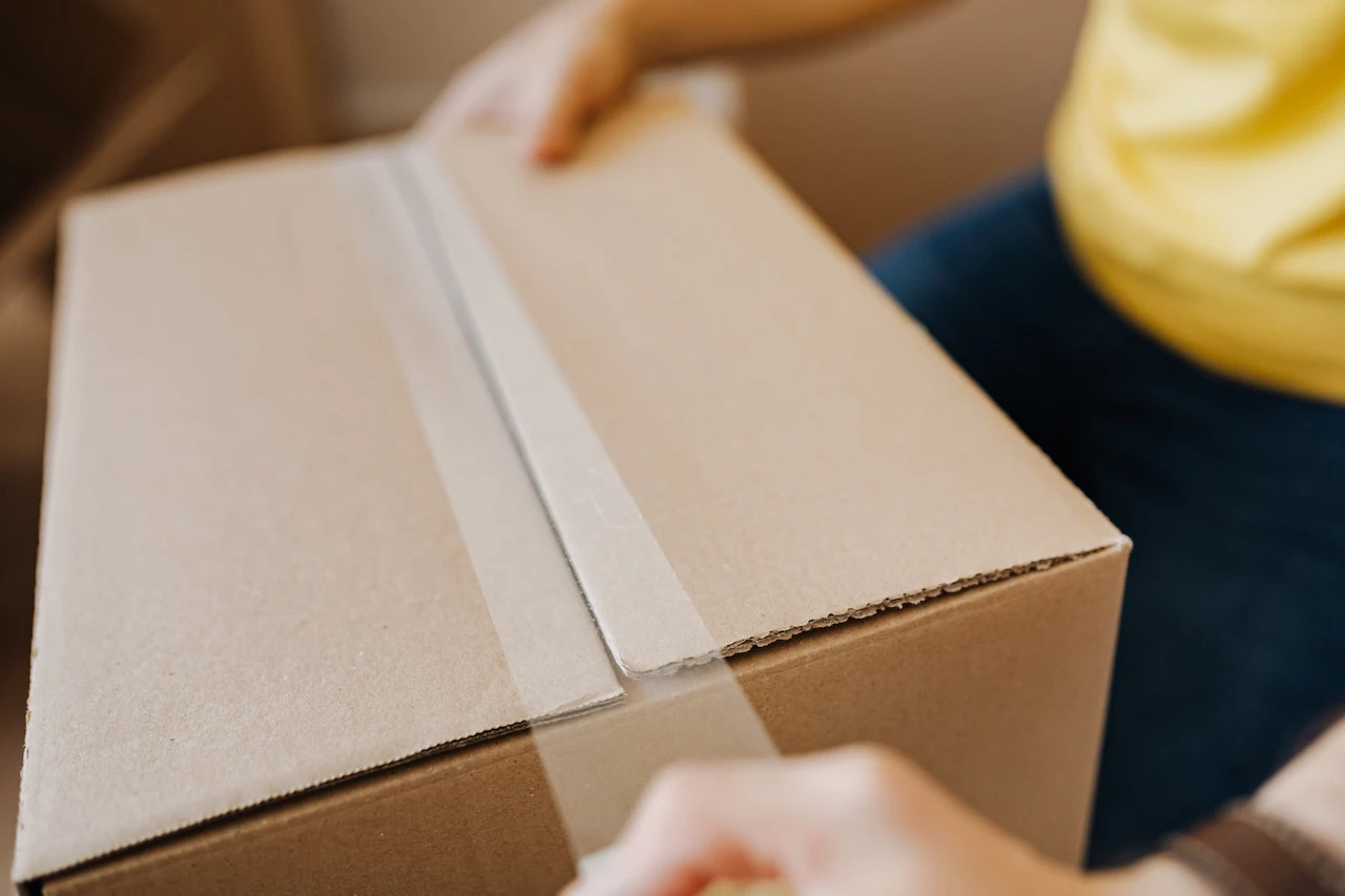 a person taping a cardboard box closed