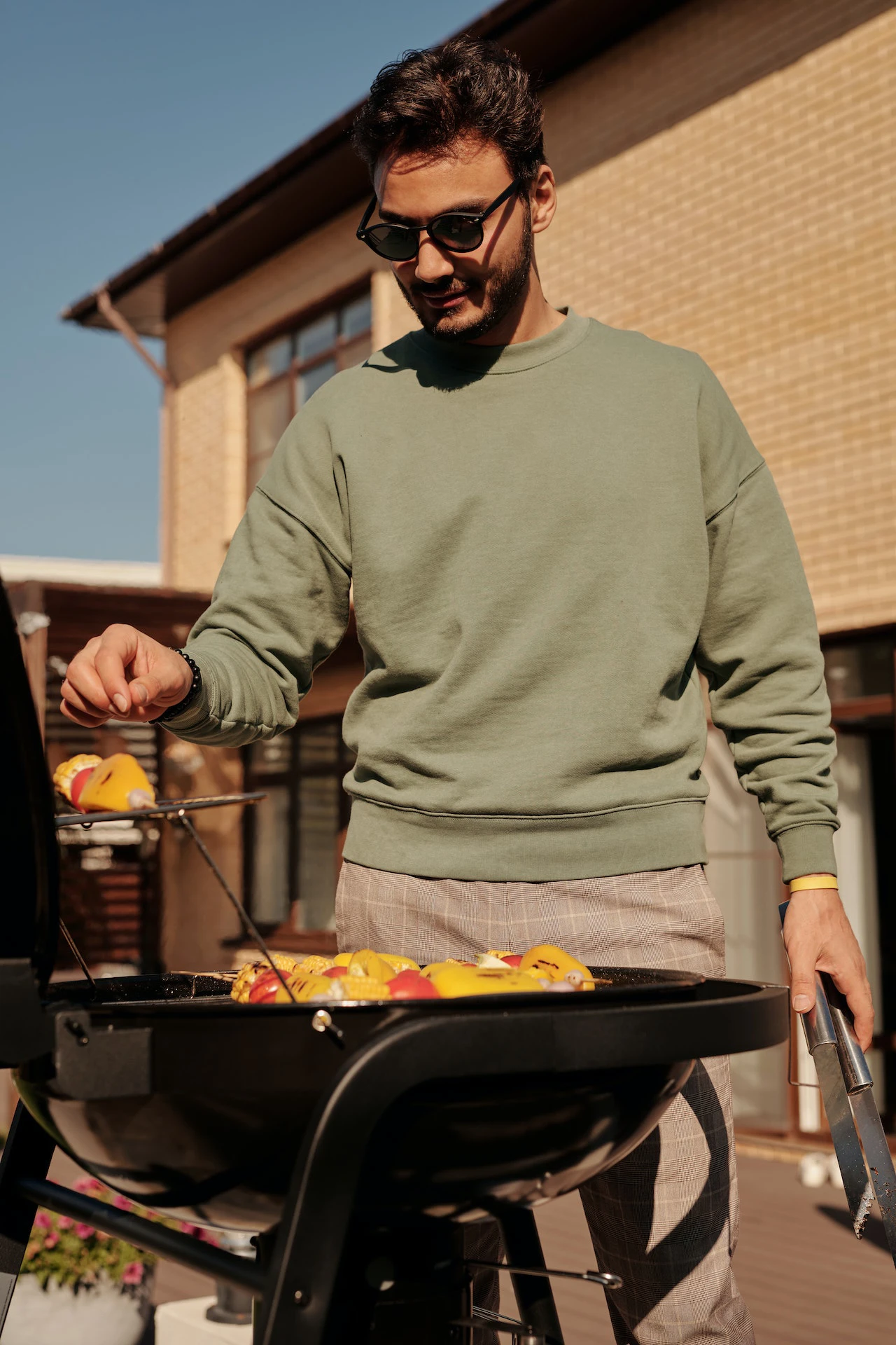 man in green pullover grilling vegetables on a BBQ